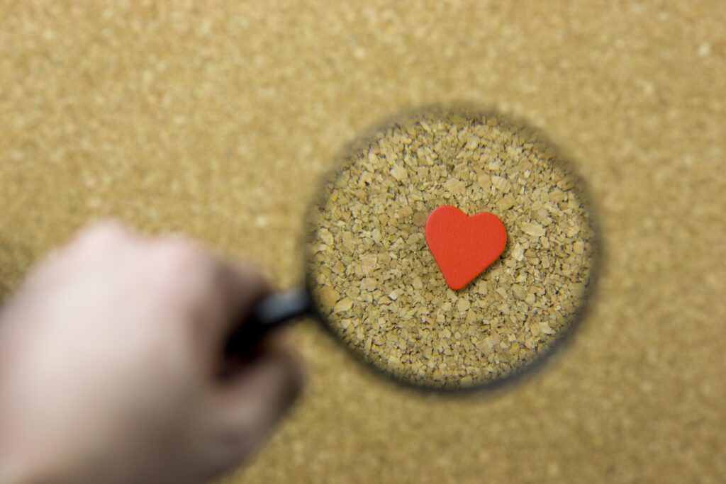 Magnifying glass on heart signifying looking for ideal clients or them looking for you